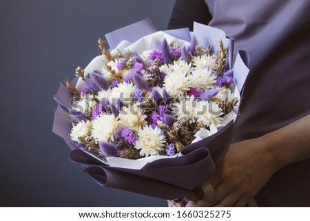 bouquet of dried flowers in the hands of a girl lavender cereal on a gray background