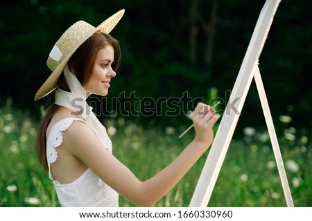young woman with a brush in her hand draws on canvas