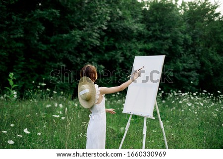young woman with a brush in her hand draws on canvas