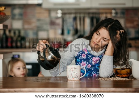 Tired mother, trying to pour coffee in the morning. Woman lying on kitchen table after sleepless night, trying to drink coffee Royalty-Free Stock Photo #1660338070