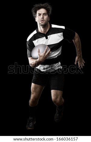 Rugby player in a black and white uniform running. black Background