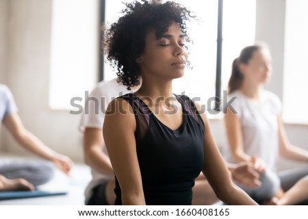 Yoga class concept, close up focus on mixed race African female closed eyes do meditation practice with associates during session. No stress, reducing fatigue after work out sport activity, wellness Royalty-Free Stock Photo #1660408165