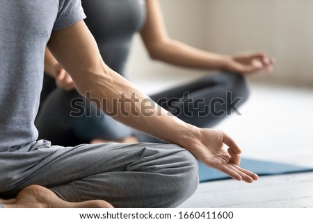 Yoga session process meditation practice close up focus on male fingers folded in mudra symbol. Concept of clarity of mind, improve inner balance, healthy lifestyle, serenity, internal calmness state Royalty-Free Stock Photo #1660411600