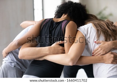 Close up rear view sport team mixed race and Caucasian diverse people before competition hugging forming circle, participants encourage each other, unity and support, engagement in common goal concept Royalty-Free Stock Photo #1660411702