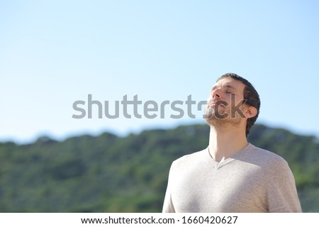 Relaxed man breathing fresh air near the mountains with a blue sky in the background Royalty-Free Stock Photo #1660420627