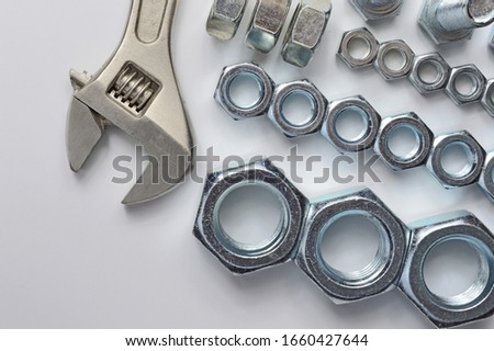 screw-nut of different sizes, bolts and adjustable spanner. White background. Concept.