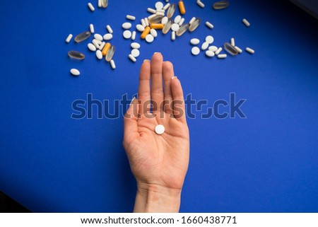 Girl scattered pills on a blue background.
Pills on the hand. Assorted pills. Medication drugs