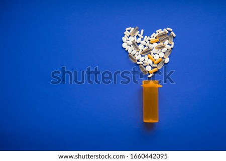 
Assorted pills on a blue background in the shape of a heart. Assorted pills. Medication