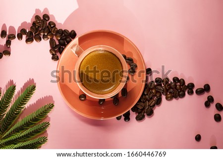 Coral colored cup with effuse coffee's beans with shadows on pastel rose background. Flat lay. Top view. Minimalism, Coffee concept. Summer still life