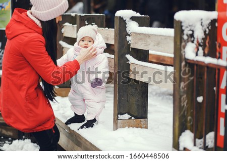Cute family have fun in a winter park. Woman in a red jacket.