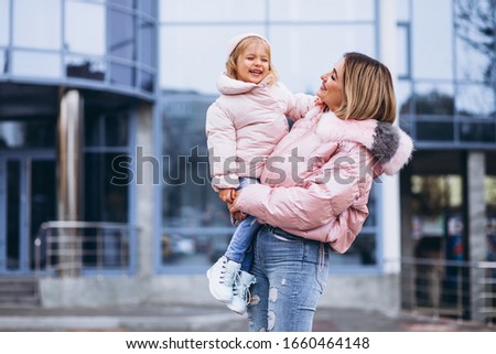 Mother with her little daughter dressed in warm cloth aoutside the street