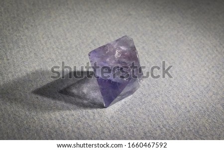 Close-up of Blue And Purple Colored Fluorite Mineral Placed on Gray Paper Background, Clearly Visible Octahedron Structure
