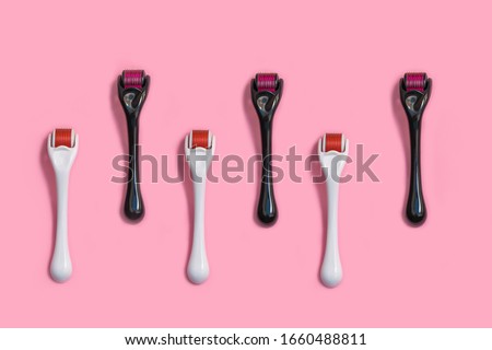 Micro needle derma roller for home face care on light pink background. Top view, flat lay, pattern Royalty-Free Stock Photo #1660488811