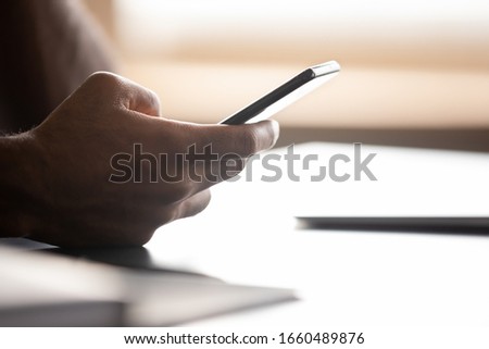 Close up focus on smartphone in african american male hands. Young biracial man holding cellphone, web surfing information, using mobile application, chatting in social networks, ordering taxi food. Royalty-Free Stock Photo #1660489876
