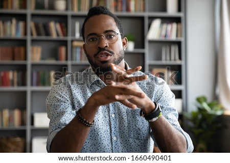 Web cam view serious concentrated young african ethnic businessman in eyeglasses holding video call negotiations with partners. Focused multiracial male job seeker talking to hr manager online. Royalty-Free Stock Photo #1660490401