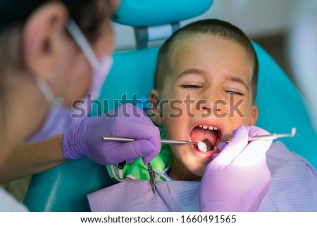 Dentists with a patient during a dental intervention to boy. Dentist Concept. At dentist's office