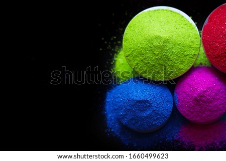 top view of colorful holi powder in bowls isolated on dark background. Space for text. 