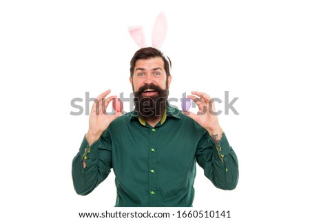 Celebration of spring holiday. Bearded man with bunny ears and Easter eggs. Hipster with long ears holding egg. Culture customs and traditions. Easter bunny delivering colored eggs. Seasonal goods.
