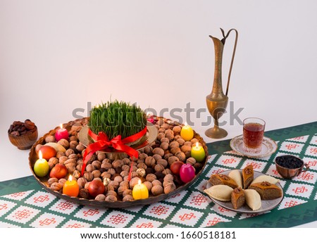 Novruz traditional tray with green wheat grass semeni or sabzi, sweets and dry fruits with samovar and shekerbura, pakhlava, candles on white isolated background. Spring equinox, Azerbaijan copy space