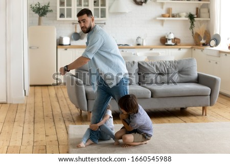 Two little kids brother and sister hold young father not letting go show affection bonding, small children siblings attached to dad, undergo parents divorce, suffer from psychological family drama Royalty-Free Stock Photo #1660545988