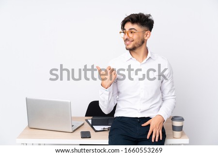 Arabian man in a office isolated on white background pointing to the side to present a product