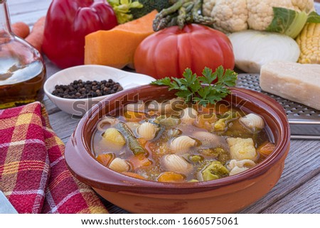 A fresh, ready to eat homemade vegetable soup. Raw vegetables on the wooden table, black pepper, olive oil and parmesan. Lifestyle healthy concept