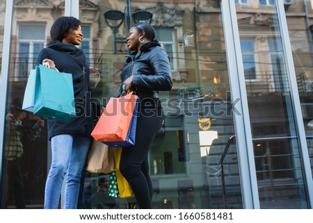 two happy African American girl friends going shopping