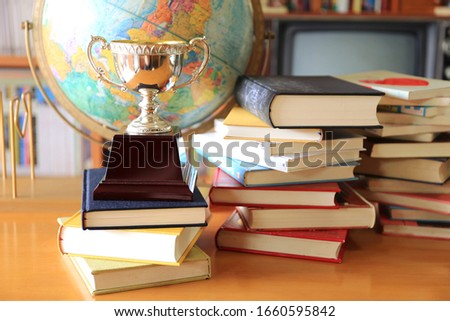 Close-up of ancient trophies on the stack of books Globe as background selective focus and shallow depth of field