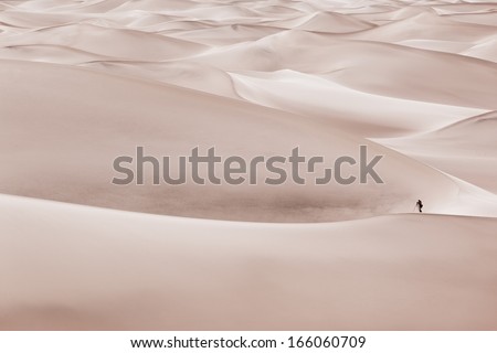A photographer in Sand dunes setting up to take a photograph. 