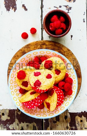 Healthy muffins with fresh raspberries in bowl on wooden table