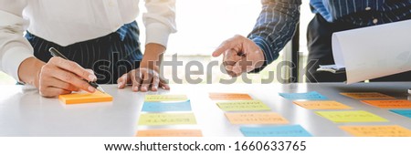 Business people arranging sticky notes commenting and brainstorming on work priorities colleague in a modern co-working space Royalty-Free Stock Photo #1660633765