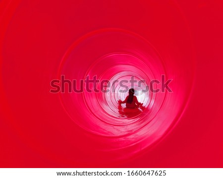 Toddler girl playing inside a red slide in the playground great fun childhood image space for test and graphics