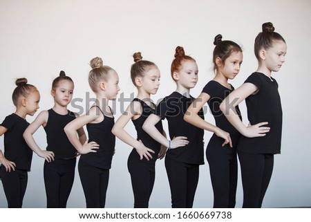 Teenage girls in black leotards are in a row at a dance, ballet or rhythmic gymnastics lesson.
