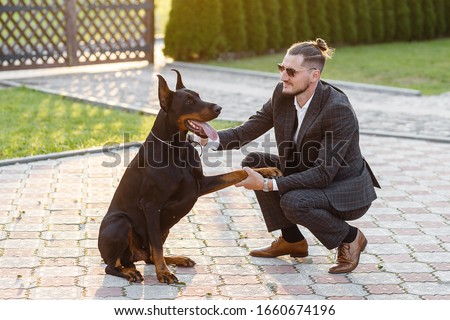 a man in a business suit on a walk with a Doberman. Doberman Training