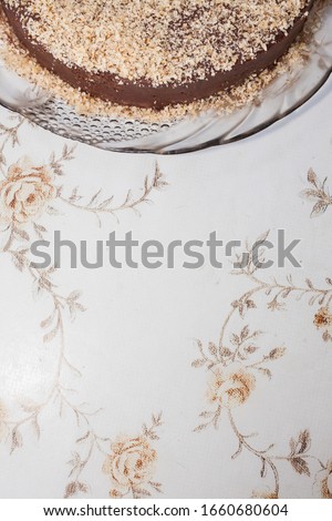 Part of a brown cake sprinkled with light brown chocolate. Part of a cake is on top of picture. Flat lays.