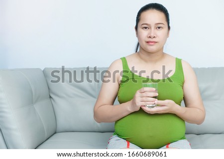 Young pregnant woman holding a glass of water which is good for her health.Nutrition and diet during pregnancy.