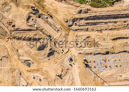 excavators and truck loaders doing earthmoving works before building construction. aerial view