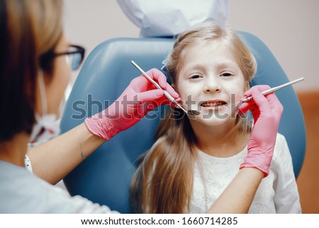 Little girl talking to the dendist. Child in the dentist's office. Woman in a uniform