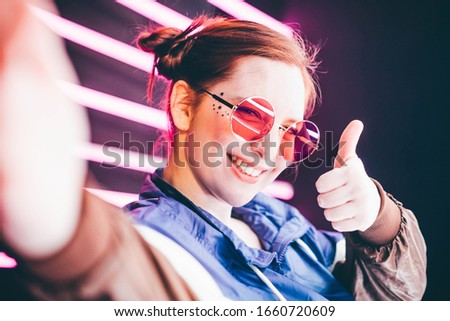 Portrait of modern young woman making selfie at the neon light.