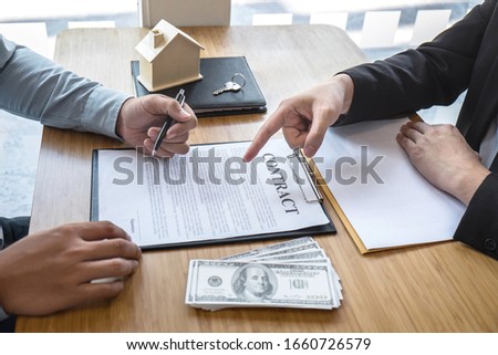 Real estate agent are presenting home loan and giving house, keys to customer after signing contract to buy house with approved property application form.