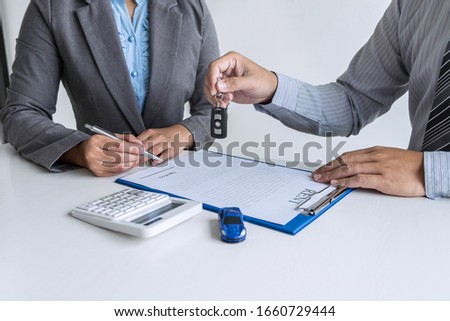 Car rent agent manager holding key of new car giving to woman client after signing good deal agreement contract, renting considering vehicle.