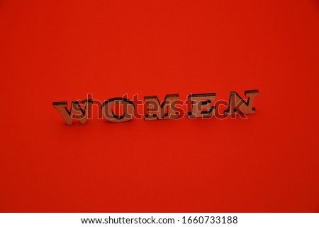 Word WOMEN mand of wooden letters standing a bit aslant isolated on red background