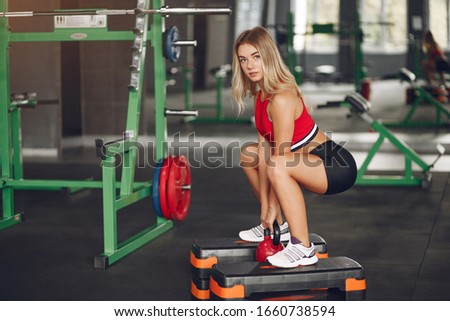 Girl in a gym. Woman with a dambbells. Lady in a red top.