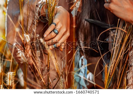 close up of woman hands wearing ethnical accessories on the field at sunset