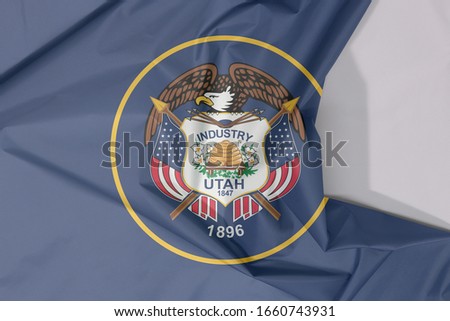 Utah fabric flag crepe and crease with white space. The seal of Utah encircled in a golden circle on a background of dark navy blue. The state of America.