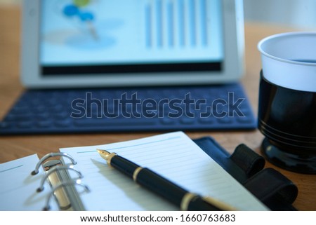 Tablet, notebook and pen on desk