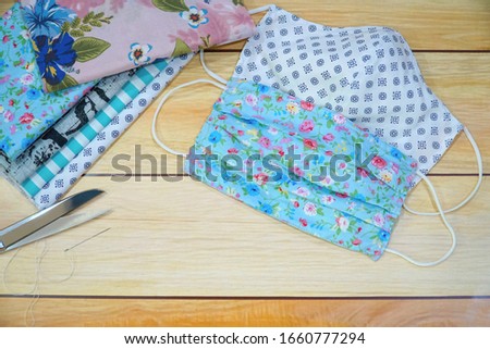Stack of cotton, scissor, needle and DIY  fabric mask on wood table. Protect dust, pollution (PM2.5), Virus, Bacteria. Handicraft, Handmade concept. Copy space for any text design. Royalty-Free Stock Photo #1660777294