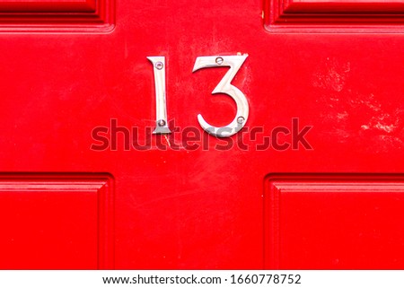 House number 13 on a red wooden front door