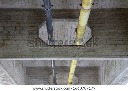 Yellow and black pipe attached under a concrete bridge construction