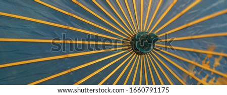 Image of a blue umbrella with yellow spokes that protects from the sun. 1930-1940 in Russia. Suitable as background, template, touristic guide, poster, greating card. Protection against sun concepts Royalty-Free Stock Photo #1660791175